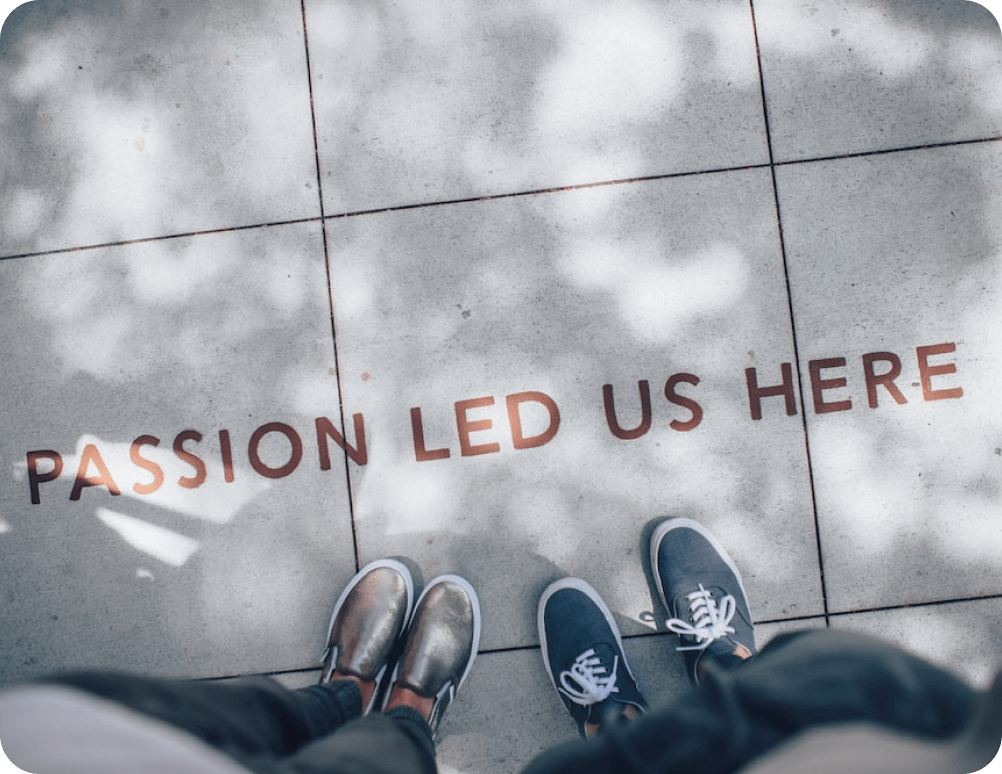 Two p2gamer.com members, standing next to a writing on the ground saying 'Passion led us here'.